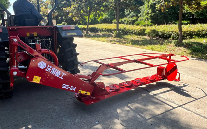 Một chiếc máy kéo màu đỏ có gắn phụ tùng máy cắt cỏ World 9G-24 đang đậu trên bề mặt lát đá.